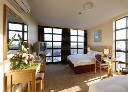 a hotel room with a bedroom with a bed and a television at Upton Court Hotel in Kilmuckridge