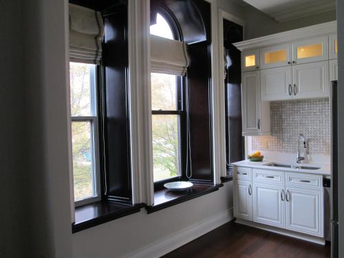 a kitchen with white cabinets and two windows at Sydney Boutique Inn & Suites in Charlottetown