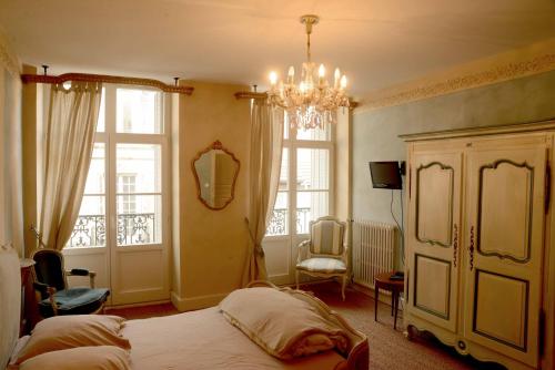 una camera con letto e lampadario a braccio di Residence des Bains a Plombières-les-Bains