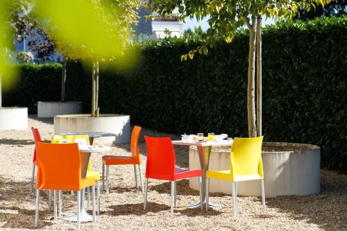 a table with colorful chairs sitting around it at Premiere Classe Tours Sud - Chambray Lès Tours in Chambray-lès-Tours