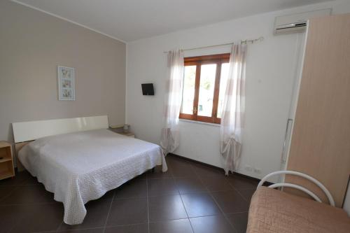a white room with a bed and a window at Villa Rosa in Modica
