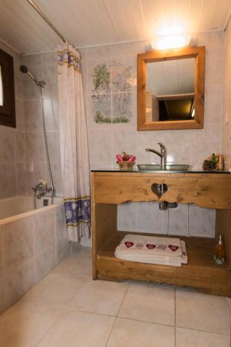 une salle de bain avec un lavabo, un miroir et une baignoire dans l'établissement Maison de la coutetta, à Morzine