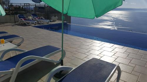 a pool with chairs and an umbrella next to a swimming pool at Villa Lilly in Podgora