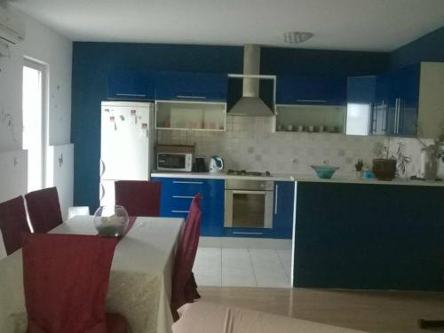 a kitchen with blue cabinets and a table with a tableablish at Apartment Roksy in Supetar