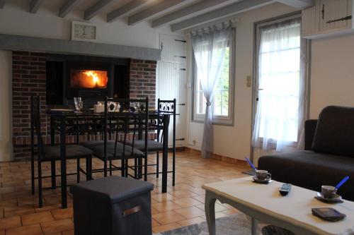 - un salon avec une cheminée, une table et des chaises dans l'établissement Ma petite Neuvillaise, à Neuville-lès-Dieppe