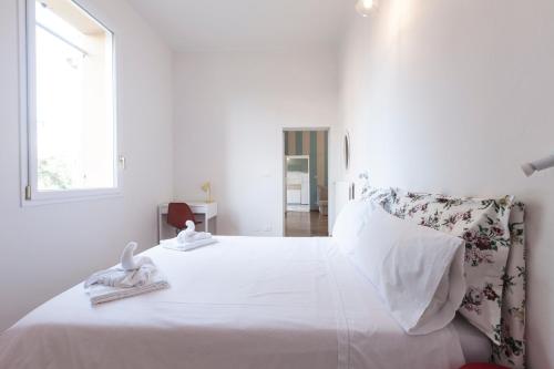 a white bedroom with a large white bed with towels on it at Saragozza Apartments - Bologna Short Rental in Bologna