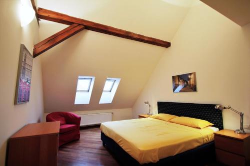 ein Schlafzimmer mit einem Bett und einem roten Stuhl in der Unterkunft Residence Salvator - by Prague City Apartments in Prag