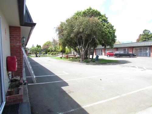 an empty parking lot next to a building with a tree at Palmerston North Motel in Palmerston North