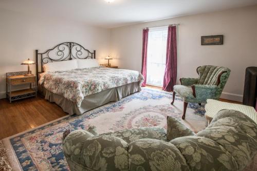 a bedroom with a bed and a couch and a chair at Village Suites in Margaretville