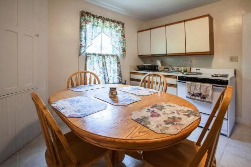 uma cozinha com uma mesa de madeira e cadeiras numa cozinha em Village Suites em Margaretville