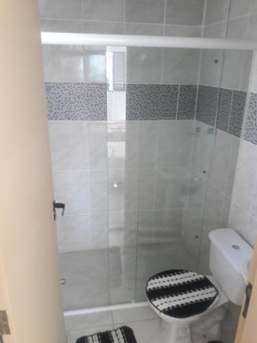 a bathroom with a shower with a black and white toilet at Pousada Acalanto Praia in Peruíbe