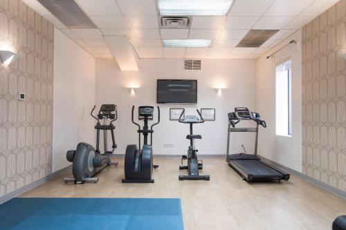 a gym with tread machines and a flat screen tv at Hôtel Albert par G5 in Rouyn