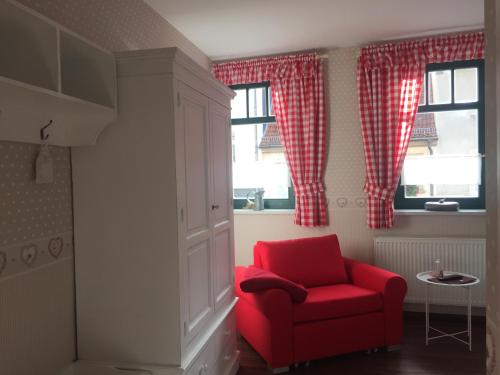 a red chair in a room with two windows at Hotel Trendtino in Eisenberg