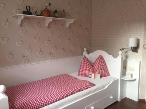 a bedroom with a white bed with red and white pillows at Hotel Trendtino in Eisenberg
