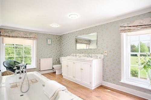 a bathroom with a tub and a sink and a toilet at Vicarage House & Pool House in Hockham
