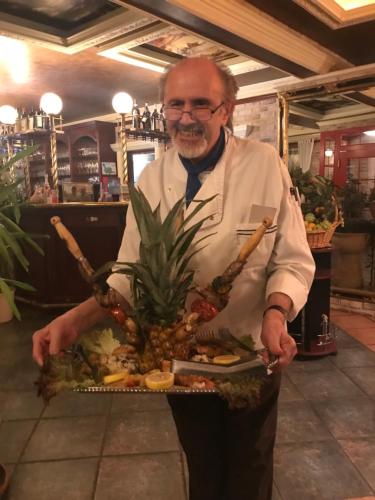 a man holding a tray of food with a pineapple at my CITY HOTEL in Eisenberg