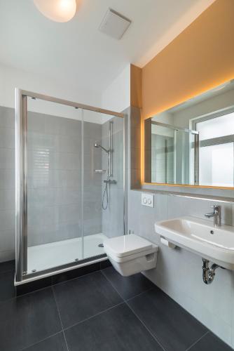 ein Bad mit einer Dusche, einem WC und einem Waschbecken in der Unterkunft Apartments Drei Morgen in Leinfelden-Echterdingen