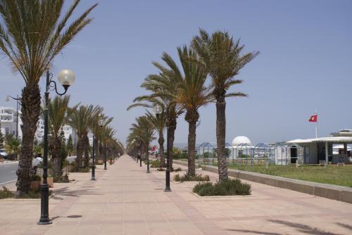 a sidewalk with palm trees and a street light at El Mouradi El Menzah in Hammamet