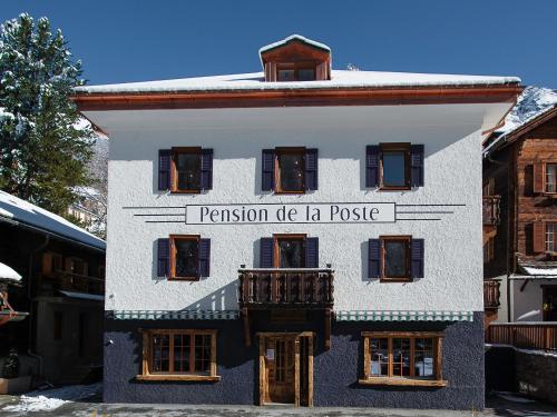 a white building with a sign on the side of it at Pension de la Poste in Zinal