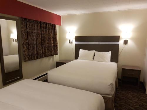 a hotel room with two beds and a mirror at Holiday Motel & RV Resort in Hope