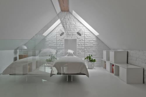 a white room with a bed and a glass table at City Entrance Apartment in Vilnius