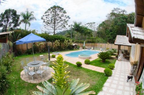 un patio trasero con piscina y sombrilla azul en Sitio Recanto dos Meus Sonhos en Teresópolis