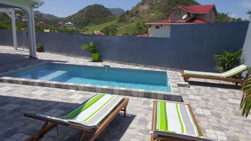 a swimming pool with two lounge chairs next to a fence at Villa Taho in Terre-de-Haut