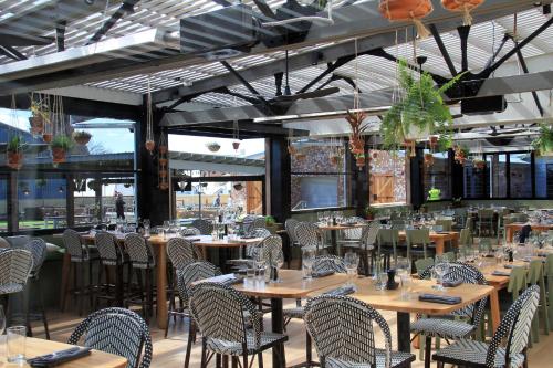 a dining room with tables and chairs and windows at Mercure Orange in Orange