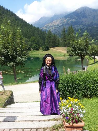 Una mujer con un vestido púrpura parada junto a un lago en Hotel Residence Lago Laux, en Fenestrelle