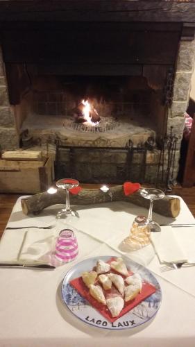 una mesa con un plato de comida frente a una chimenea en Hotel Residence Lago Laux, en Fenestrelle