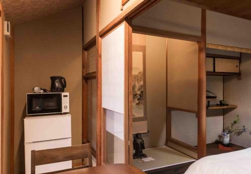京都的住宿－丸子旅館京都酒店，一间小卧室,配有双层床和微波炉