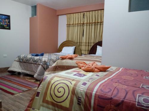 Dos camas en una habitación con toallas. en Hostal Intiwatana Inn, en Puno