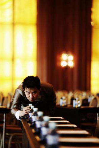 a man sitting at a table looking at his cell phone at V-Continent Beijing Parkview Wuzhou Hotel in Beijing