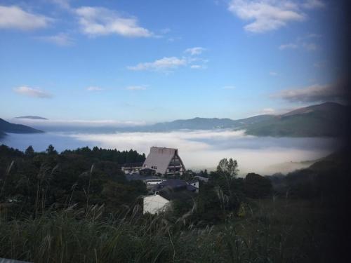 a view of a building in the middle of a foggy valley at Yufuin-Sanso Waremokou in Yufuin