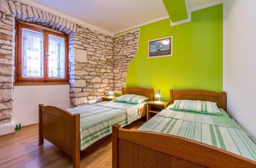 two beds in a room with green walls and wooden floors at Apartments Lorencin in Medulin