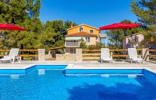 a house with a swimming pool and two umbrellas at Apartments Puntica in Ližnjan