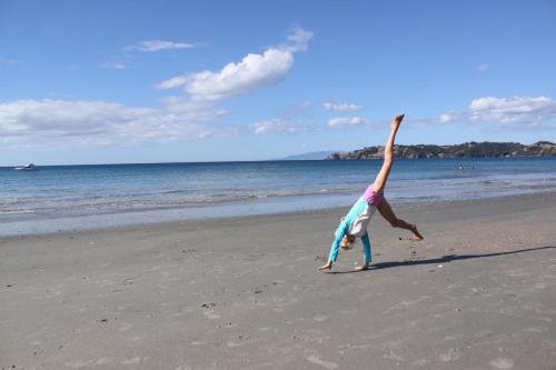 a young girl doing a handstand on the beach at Waiheke Island Motel in Ostend