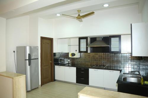 a kitchen with white cabinets and a ceiling fan at Swan Suites Madhapur in Hyderabad