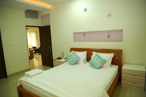 1 dormitorio con 1 cama con sábanas blancas y almohadas azules en Swan Suites Madhapur, en Hyderabad