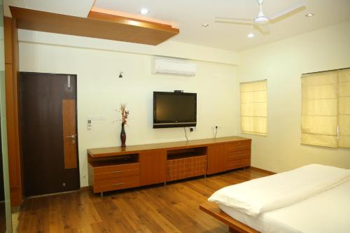 a bedroom with a bed and a tv on the wall at Swan Suites Madhapur in Hyderabad