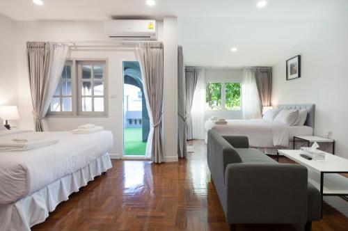 チェンマイにあるコージー ホーム バイ ナンの白いベッドルーム(ベッド2台、ソファ付)