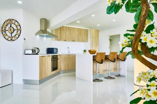 an open kitchen with wooden cabinets and bar stools at LUXURIOUS APARTMENT on JOMTIEN BEACH ROAD in Jomtien Beach