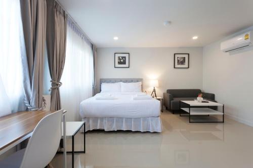 a bedroom with a bed and a couch and a table at Cozy Home by Nan in Chiang Mai
