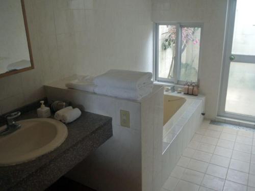 ein Badezimmer mit einer Badewanne, einem Waschbecken und einer Badewanne in der Unterkunft Beach Village Nosoko in Ishigaki-jima