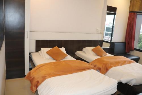two beds with orange pillows in a room at Hotel Raj in Aurangabad