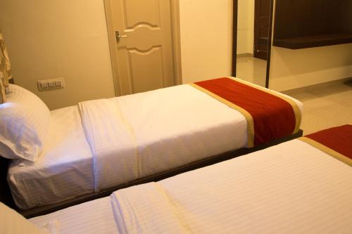 two beds in a room with a mirror at Hotel Blue Bell in Bengaluru