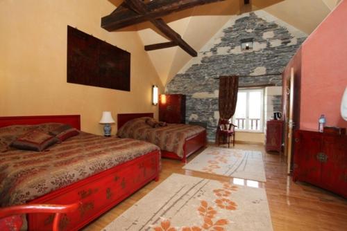 a bedroom with two beds and a stone wall at Château de Belle Poule in Les Ponts-de-Cé