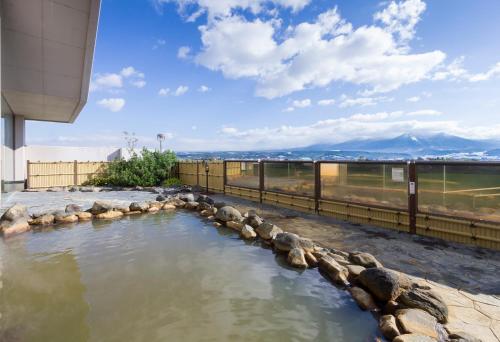 a pool of water with rocks in front of a building at SPA&HOTEL RESORT Furano La Terre in Nakafurano