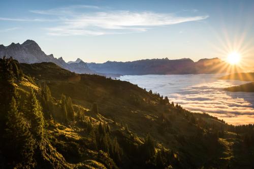 a view of a mountain with the sun rising over the clouds at Kaiserhaus Leogang in Leogang