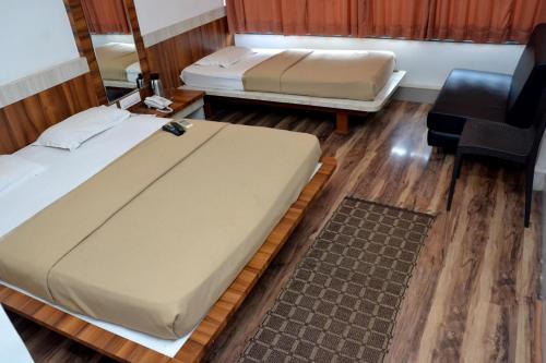 a bedroom with two beds and a chair at Hotel Raj in Aurangabad